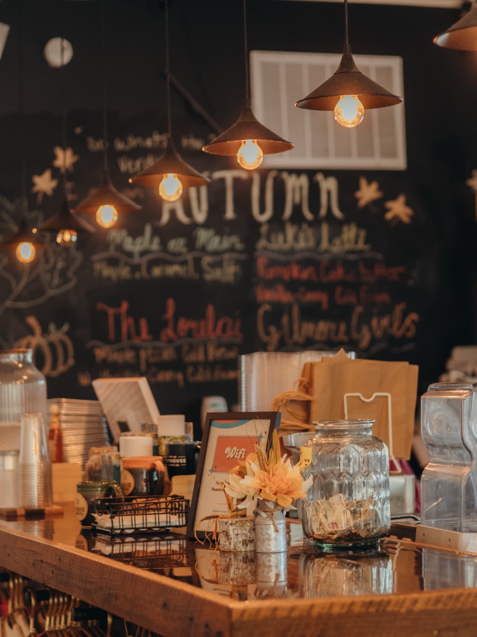 The Joyhouse bar under pendant lights, the autumn drinks chalked on the board behind it